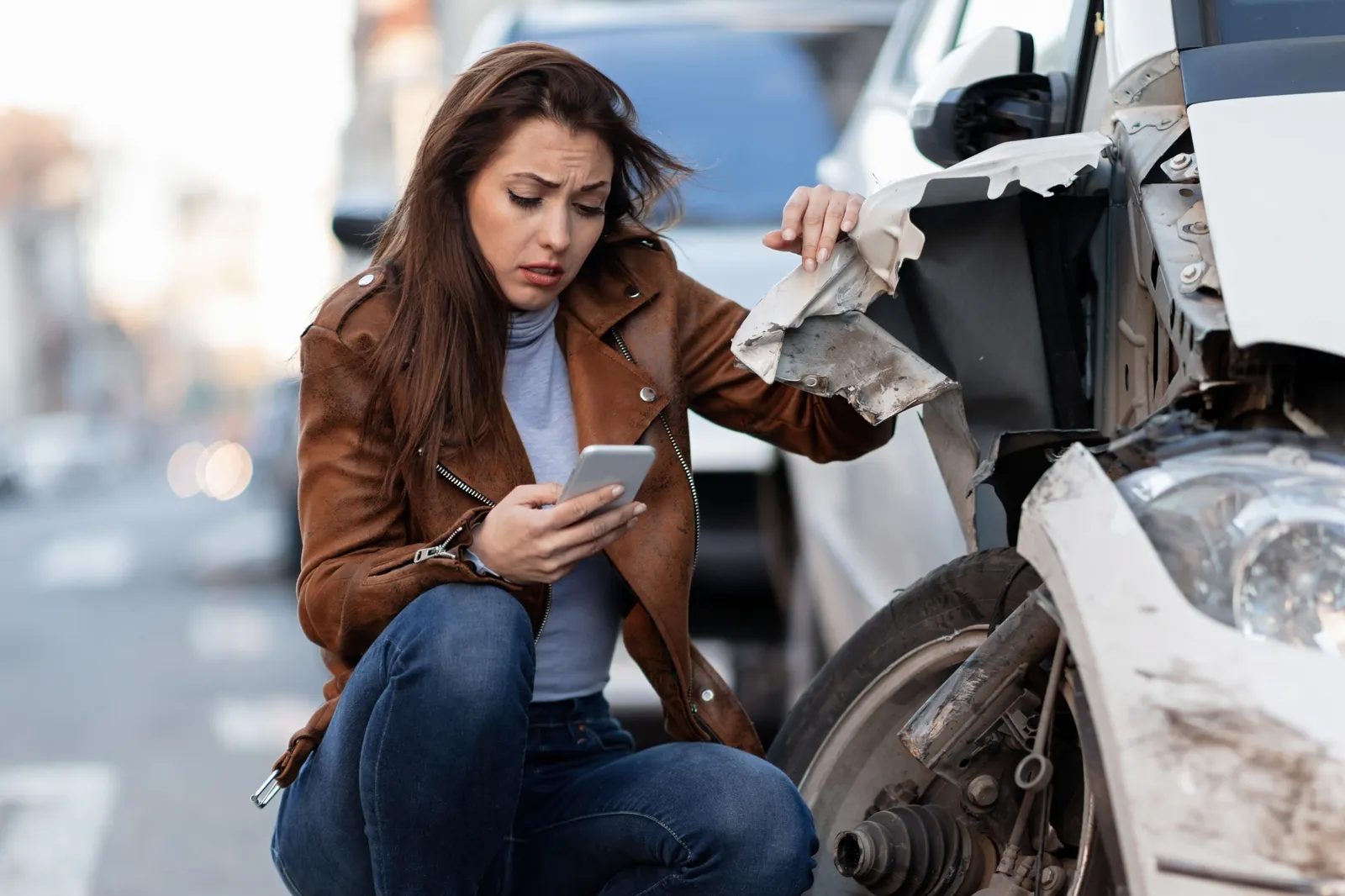 A shaken driver crouched beside her damaged car at the roadside after a collision