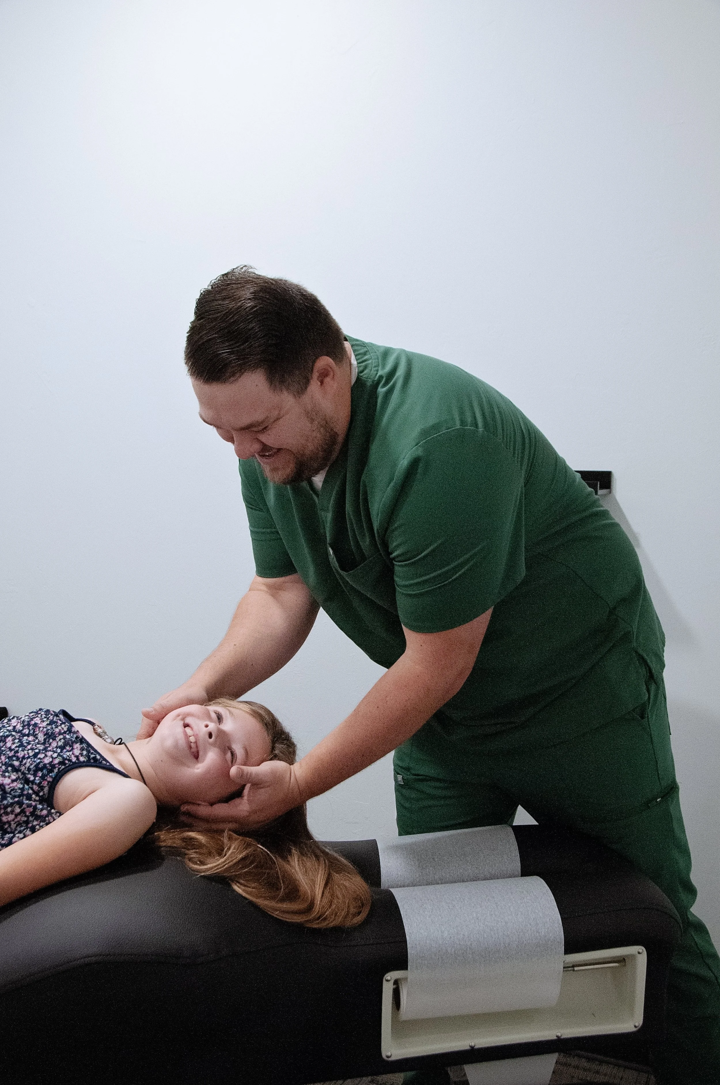 Dr. Jake Edwards giving a gentle chiropractic check to a young child